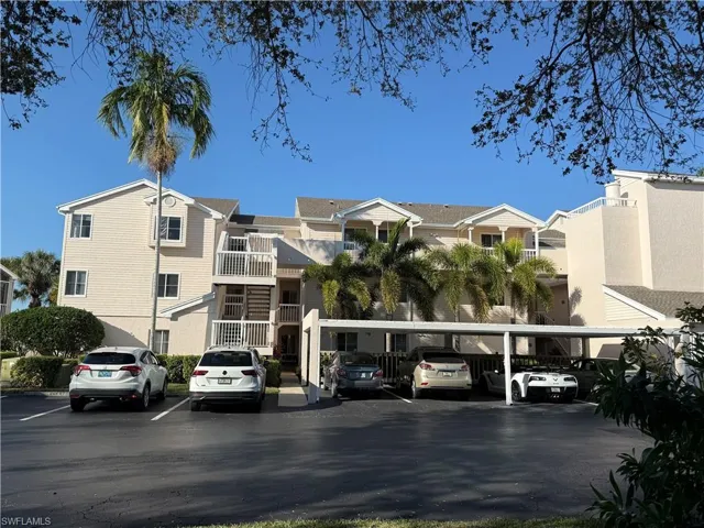 View of building exterior with covered and uncovered parking