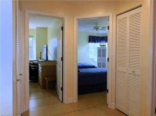 Hallway with light tile patterned flooring and a desk