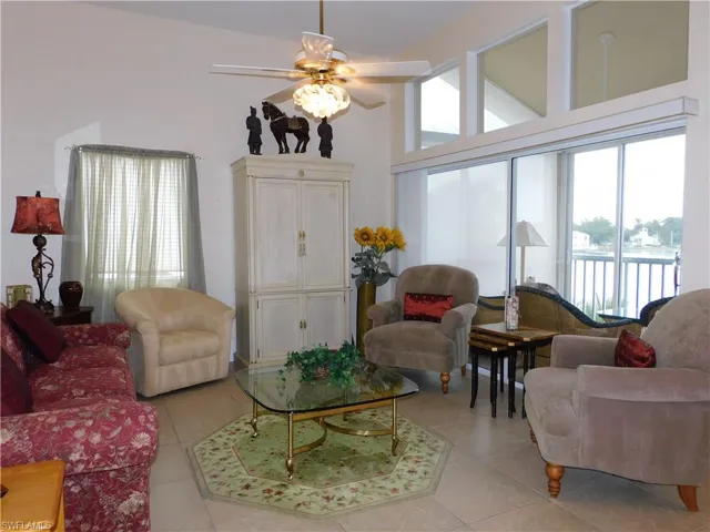 Living area with a ceiling fan, a high ceiling, a water view, and light tile patterned floors