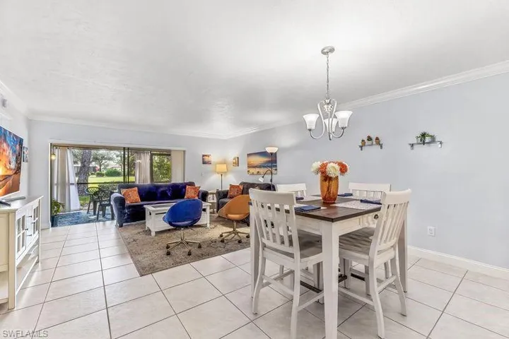 Dining/Living space featuring light tile patterned flooring, ornamental molding, and a chandelier
