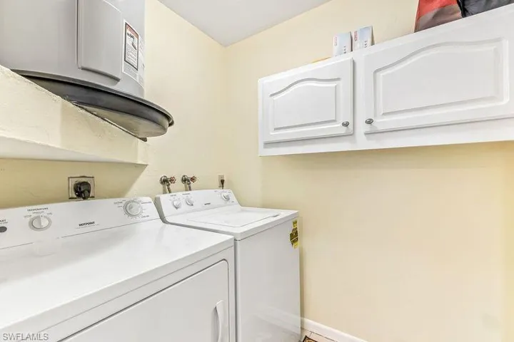 In unit laundry/storage area with cabinets, water heater, and washer and dryer