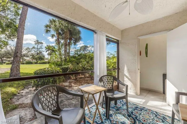 Screened lanai with ceiling fan, view of storage area, and view of golf course
