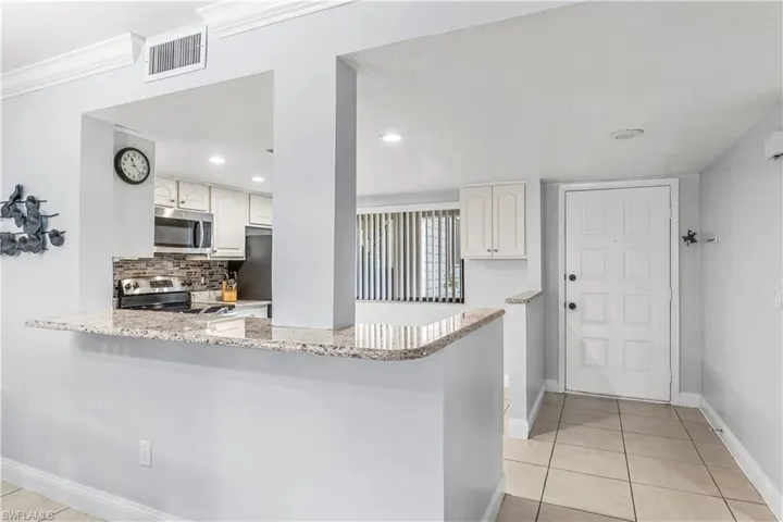 Kitchen with kitchen peninsula, appliances with stainless steel finishes, decorative backsplash, and white cabinetry
