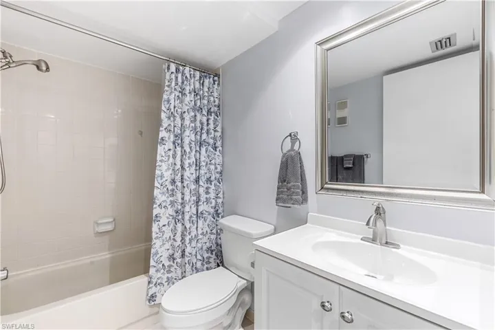 Full guest bathroom featuring vanity, shower / bath combo, and toilet