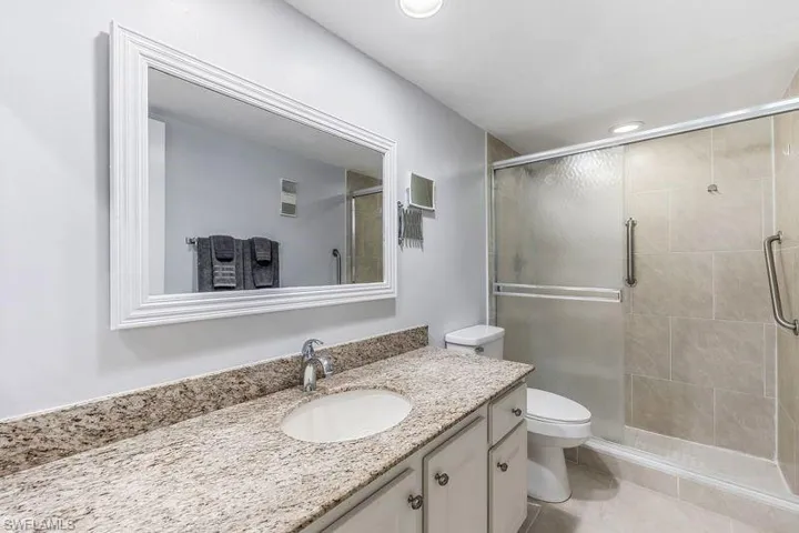 Master bathroom featuring tile patterned flooring, vanity, toilet, and a tiled shower with glass door