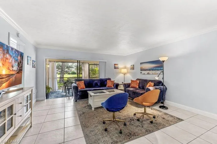 Tiled living room featuring crown molding and view of the golf course