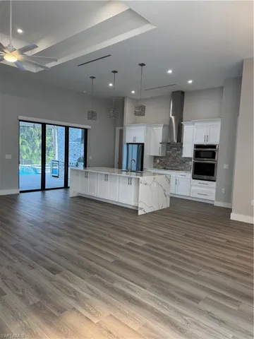 Kitchen with a large island with sink, white cabinetry, hardwood / wood-style floors, and ceiling fan