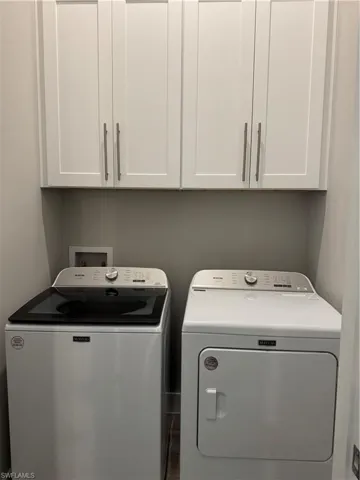 Washroom featuring washer, dryer and cabinets