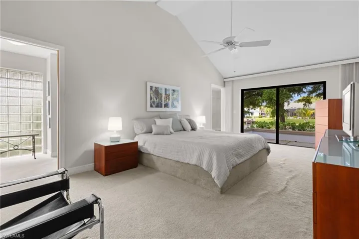 Carpeted bedroom featuring ceiling fan, access to exterior, and high vaulted ceiling