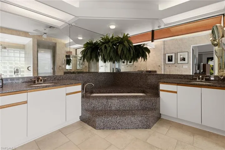 Bathroom featuring quartz countertops, double sinks, and large soaking tub