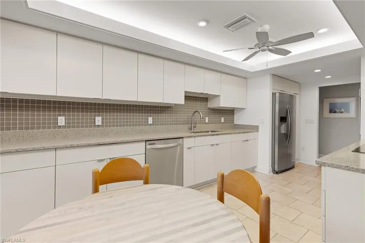 Kitchen featuring ceiling fan, tasteful backsplash, stainless steel appliances, white cabinets, quartz countertops and breakfast nook