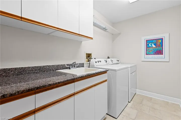 Laundry area featuring sink, washer and dryer, cabinets, and light tile patterned floors