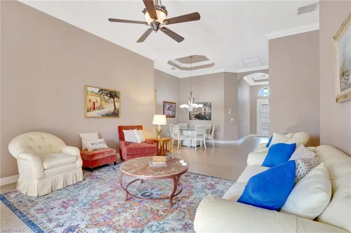 Living room featuring arched walkways, visible vents, a ceiling fan, and baseboards