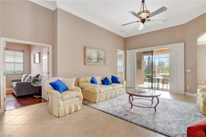 Living room featuring ceiling fan, baseboards, ornamental molding, and tile patterned floors