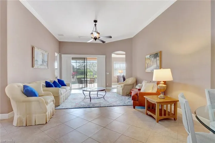 Living room featuring ceiling fan, baseboards, arched walkways, and ornamental molding