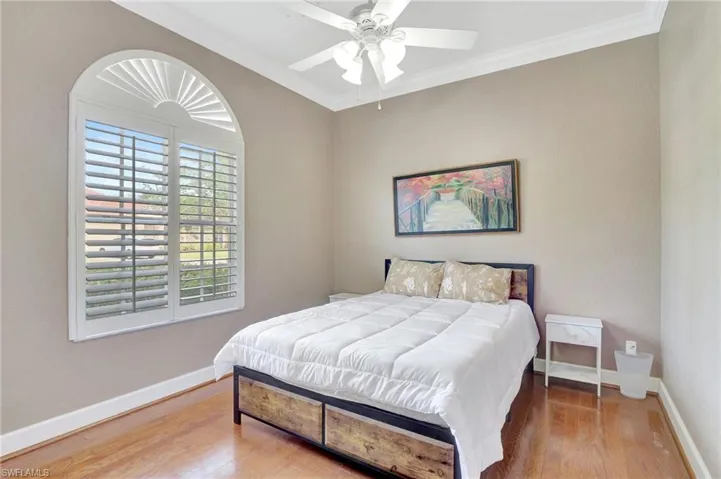Bedroom featuring baseboards, crown molding, and wood finished floors