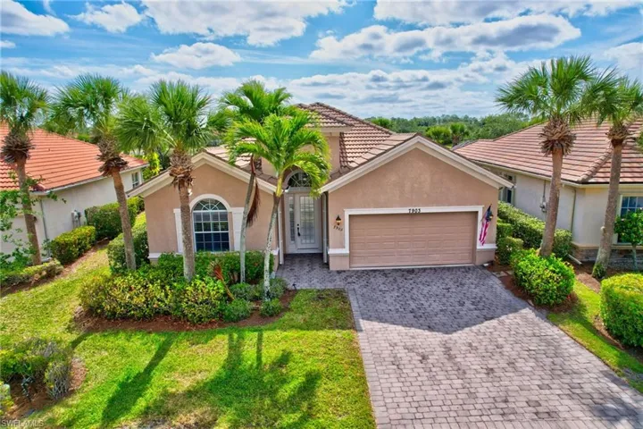 Mediterranean / spanish house with an attached garage, a front lawn, stucco siding, and decorative driveway