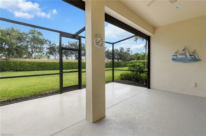 Screened lanai featuring a concrete floor, recessed ceiling lighting, a structural support column, and an expansive fenced backyard with established landscaping