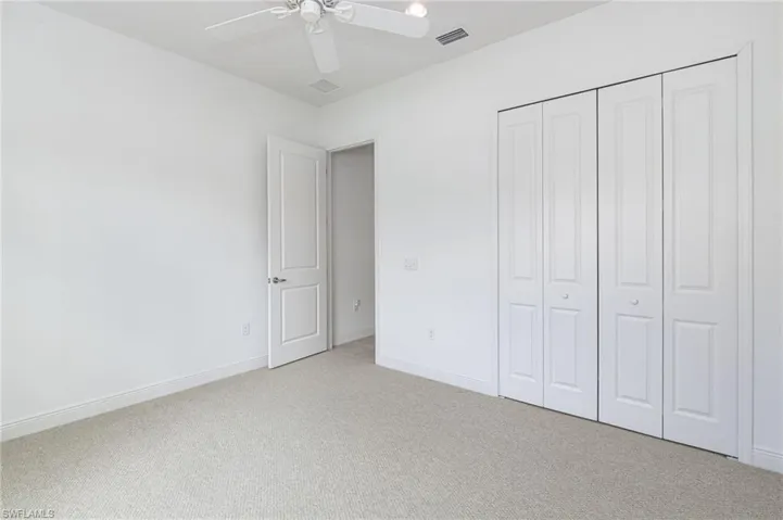 Neutral carpeting, white interior doors, bi-fold closet doors, and a ceiling-mounted light fixture