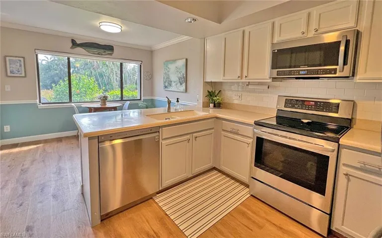Kitchen featuring stainless steel appliances, white cabinetry, and sink