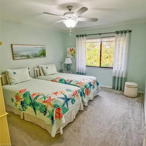 Carpeted bedroom featuring ceiling fan and crown molding