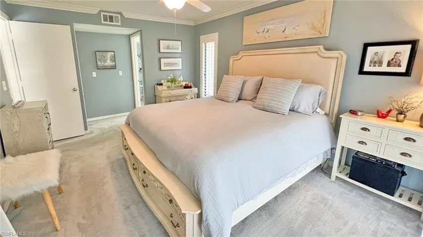 Carpeted bedroom featuring ceiling fan and ornamental molding