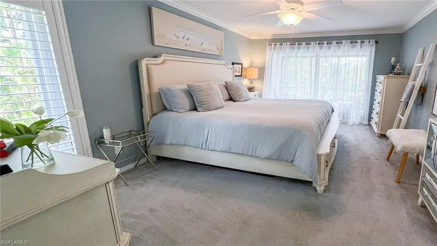 Carpeted bedroom with multiple windows, crown molding, and ceiling fan