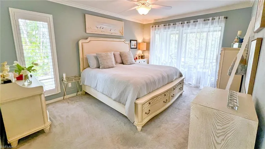 Carpeted bedroom with ceiling fan and ornamental molding