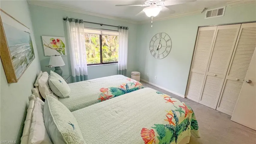 Carpeted bedroom featuring ceiling fan, a closet, and crown molding