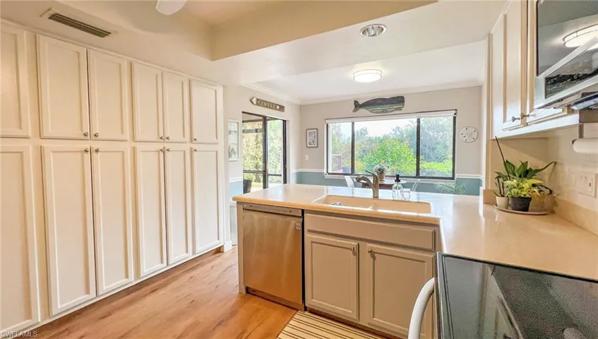 Kitchen featuring dishwasher, light hardwood / wood-style floors, crown molding, and sink