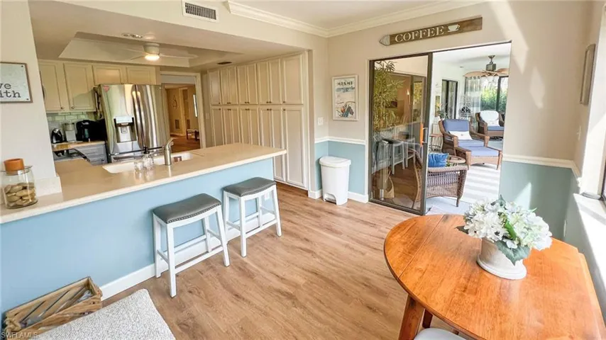 Kitchen featuring sink, stainless steel refrigerator with ice dispenser, light hardwood / wood-style flooring, ceiling fan, and a tray ceiling