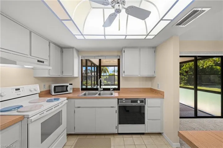 Kitchen featuring white appliances, light countertops, light tile patterned flooring, and white cabinetry