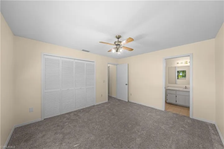 Unfurnished bedroom featuring light colored carpet, a closet, and a ceiling fan