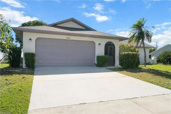 Single story home featuring stucco siding, concrete driveway, a garage, a front lawn, and roof with shingles