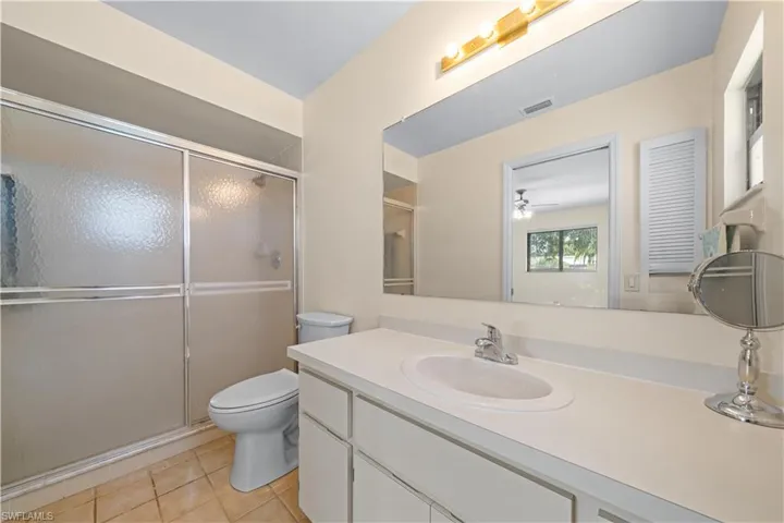 Bathroom featuring vanity, light tile patterned floors, a stall shower, and a ceiling fan