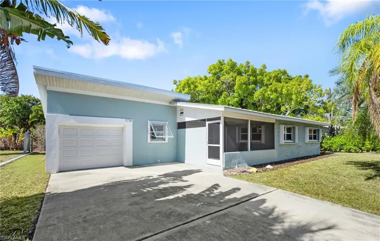 View of front of property with concrete driveway, a front yard, stucco siding, a garage, and a sunroom
