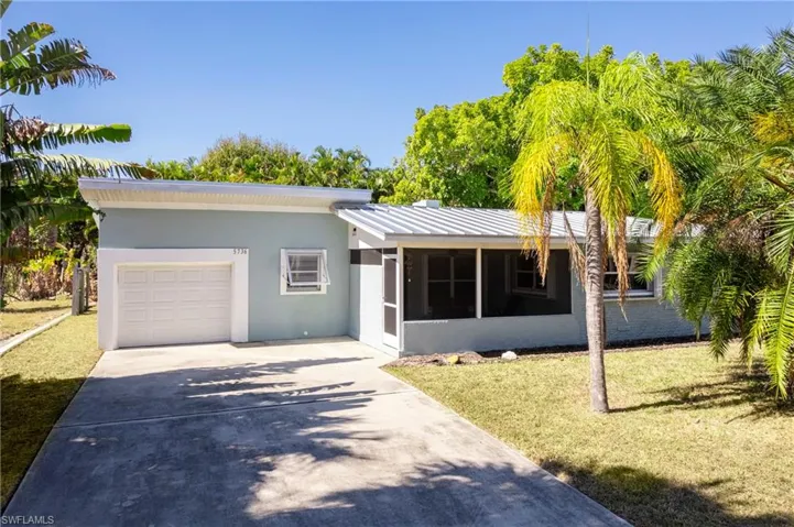 Ranch-style house featuring concrete driveway, stucco siding, a standing seam roof, a garage, and a sunroom