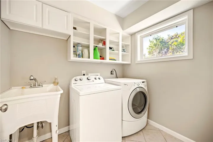 Laundry area with washing machine and dryer and light tile patterned flooring