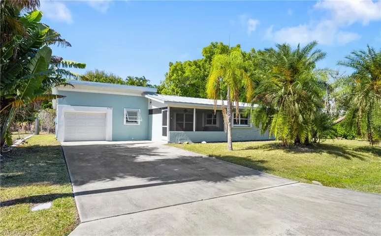 Ranch-style house featuring driveway, a front lawn, a garage, stucco siding, and a metal roof