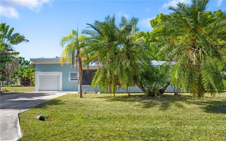 View of front of property with driveway, a front yard, stucco siding, and an attached garage