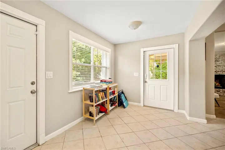 Doorway to outside with healthy amount of natural light, tile patterned flooring, and a large fireplace