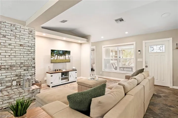 Living area featuring lofted ceiling, stone finish floors, and recessed lighting
