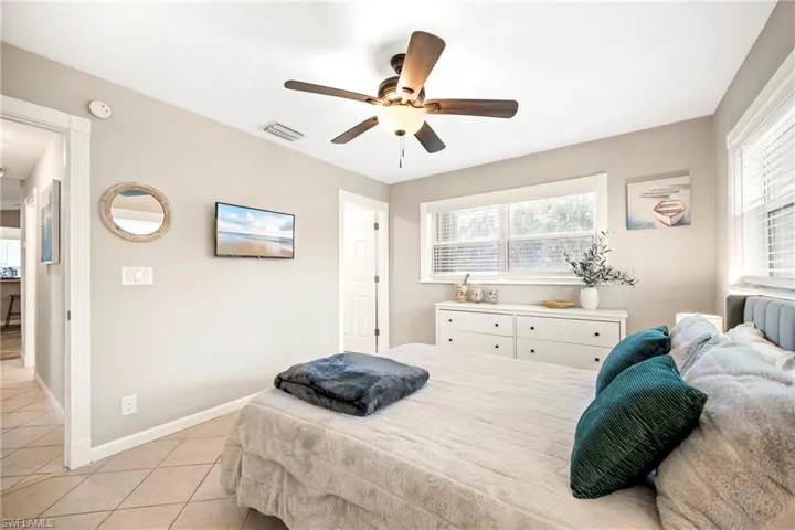 Bedroom featuring multiple windows, light tile patterned floors, and a ceiling fan