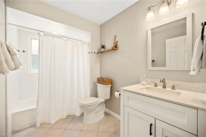 Bathroom with vanity, shower / bath combo, and light tile patterned floors
