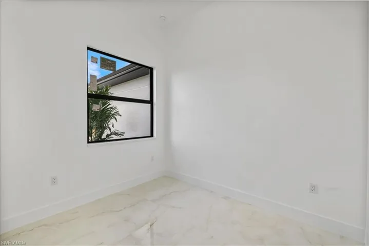 Spare room featuring baseboards and light marble finish floors