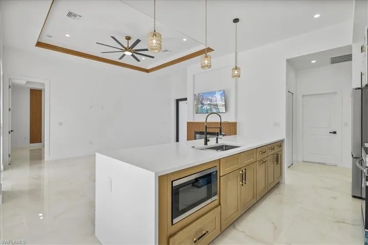 Kitchen with light marble finish floors, a peninsula, decorative light fixtures, appliances with stainless steel finishes, and recessed lighting