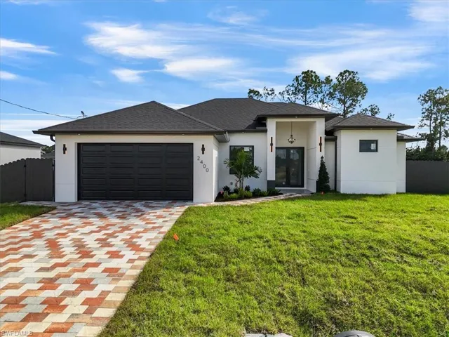 Prairie-style house featuring stucco siding, decorative driveway, and a garage