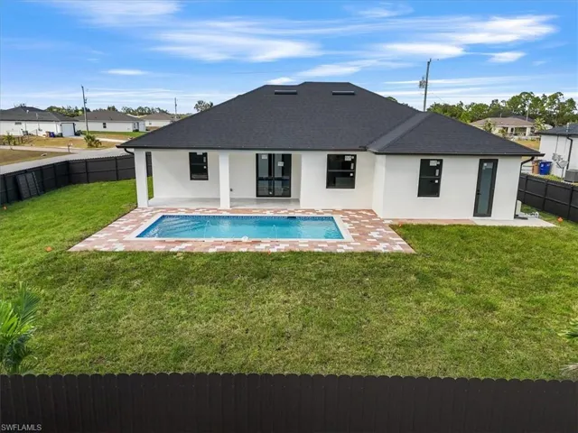 Back of property with stucco siding, a fenced backyard, a patio area, and a shingled roof
