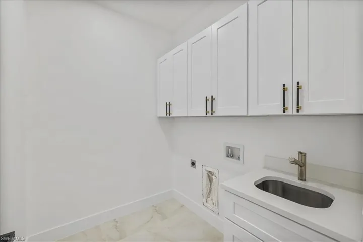 Laundry area featuring light marble finish flooring, hookup for an electric dryer, hookup for a washing machine, and cabinet space