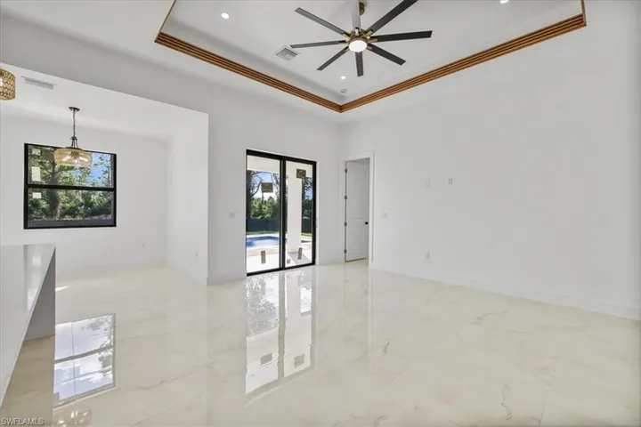 Spare room with light marble finish flooring, a ceiling fan, a raised ceiling, crown molding, and recessed lighting
